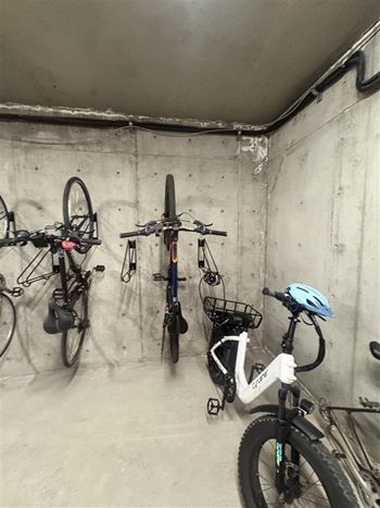 A bicycle with a blue helmet is leaning against a wall with other bicycles hanging on it.